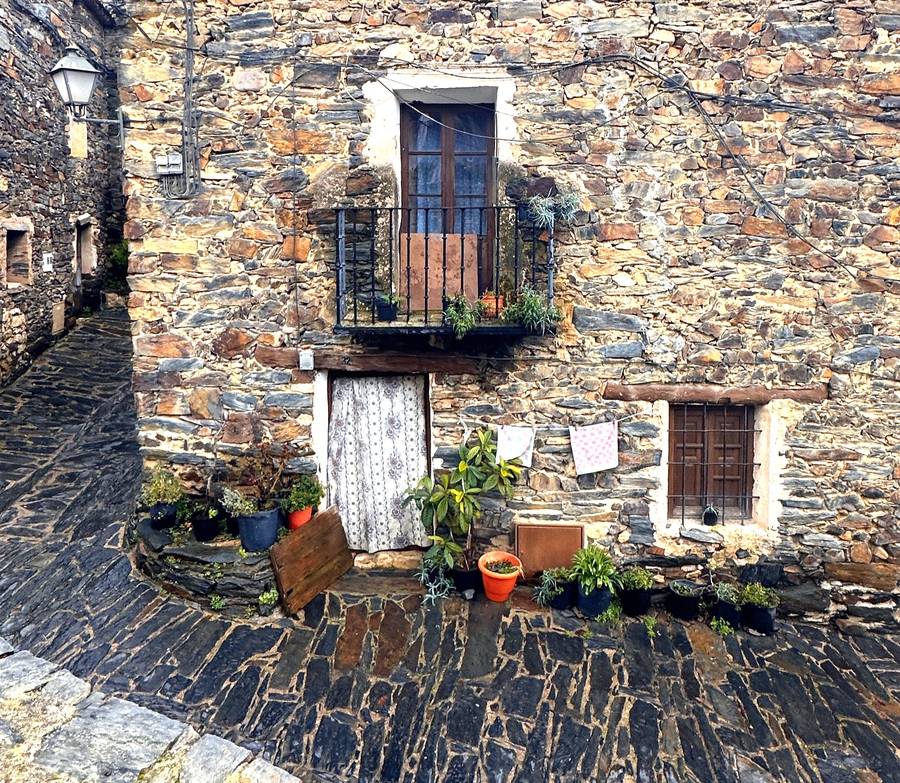 Fachada de piedra con balcón y macetas